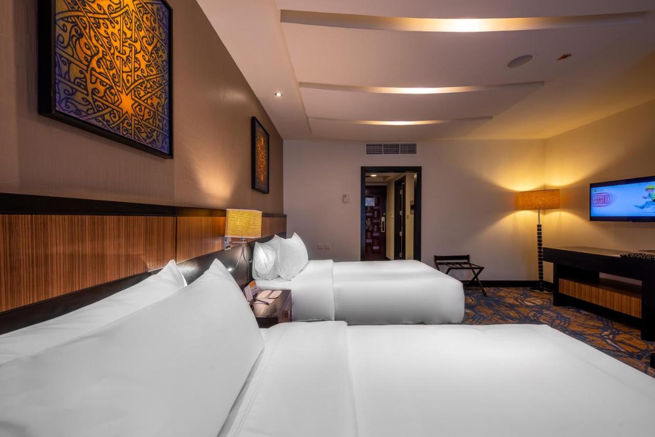 Al Ghufran Safwah Hotel Makkah Mekka Eksteriør billede The photo shows a modern hotel room featuring two beds with white linens placed side by side. There are decorative elements on the walls, including artworks that appear to be framed and feature intricate designs. The room has ambient lighting, with a